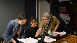 Two students working with piano instructor